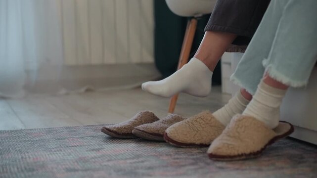 White tutor feet beside slippers calm home grammar coaching student and tutor sitting on chairs soft rug fuzzy slippers denim jeans patient guidance warm natural light intimate domestic study scene