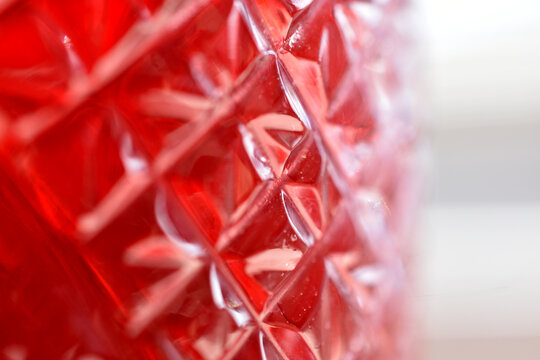 A textured background created by a bright red glass object with a faceted diamond pattern.
