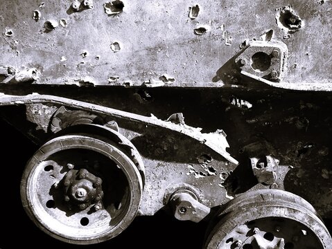 Monochrome damaged military BTR armor texture. Black and white destroyed armored personnel carrier hull with bullet holes and shrapnel impacts close-up.