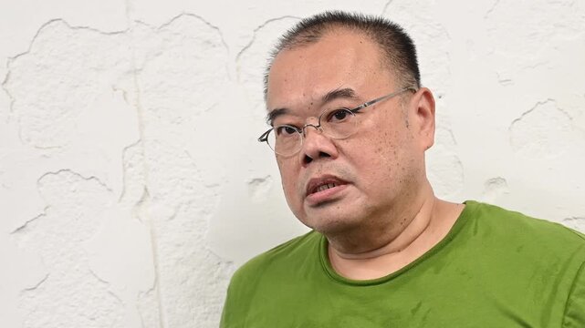 Overweight man exercise indoor portrait wearing green shirt glasses tired sweating against textured wall casual adult health fitness determination focused expression