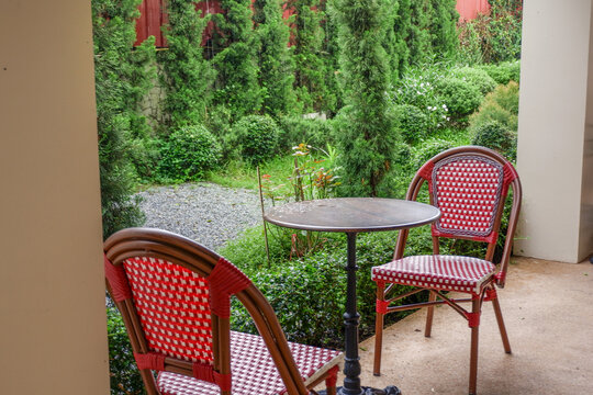 Luxury chair and wooden table set in english garden on a sunny day,outdoor seating for restaurant or cafe,Near paver patio with sitting area and small garden in forest.