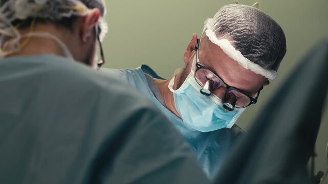 Surgeons in sterile protective clothing working together during an operation. Concept surgical collaboration, precision medicine, modern healthcare and patient care.