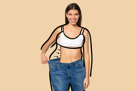 Slim woman pulling large oversize jeans to show results of her dieting and fitness workouts