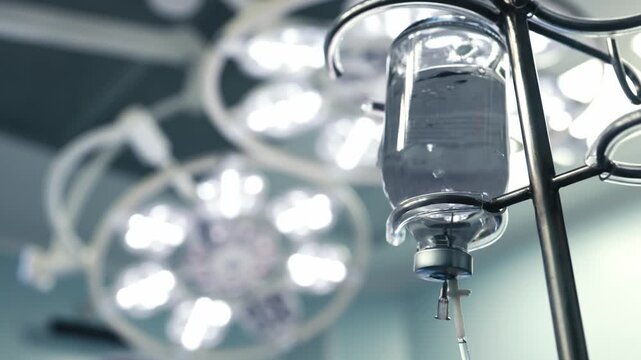 Clear infusion solution prepared on an IV stand in a modern operating room. Concept intravenous treatment, surgical care and modern medical technology.