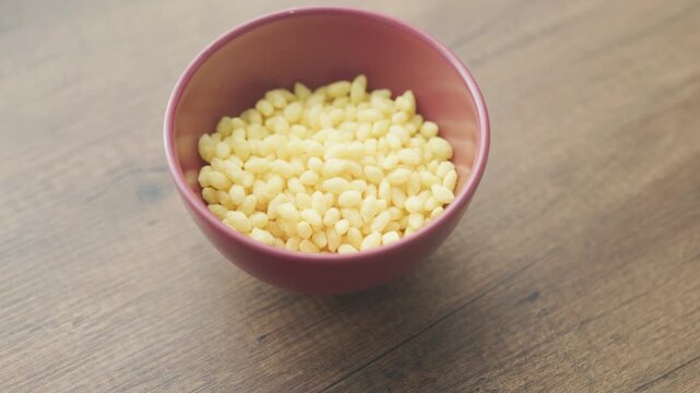 Close-up of tiny crunchy corn chip pieces in a red ceramic bowl