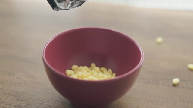 Close-up of tiny crunchy corn chip pieces in a red ceramic bowl