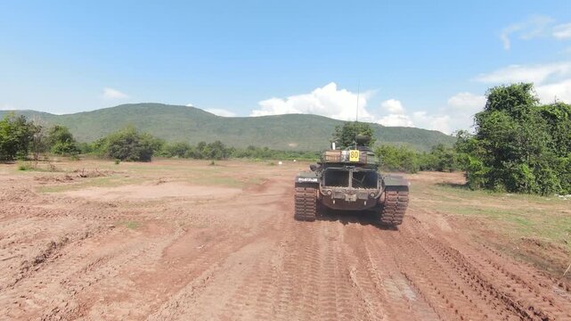 THAILAND - AUGUST 9, 2026: Heavy military battle tank operating in field training grounds, showing external armor tracks and interior tactical command cockpit equipment inside a restricted military zo