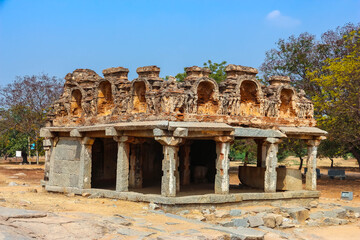 Fototapeta premium Ancient stone temple ruins and historic carved architecture in Hampi, India. Beautiful landscape with archaeological site, cultural heritage landmark and popular international tourist destination.