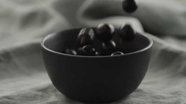 Slow motion ripe blackcurrant falling in ceramic bowl