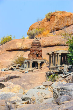 Ruins of ancient stone temples and structures nestled among massive granite boulders in Hampi, India. Historic Hindu architecture, archaeological site, cultural heritage monument and landmark.