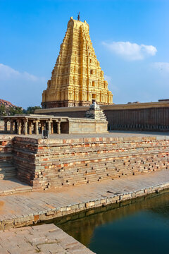 View of the majestic gopuram tower of the ancient Virupaksha Temple against a blue sky in Hampi, India. Historic Hindu architecture, cultural heritage monument and landmark.