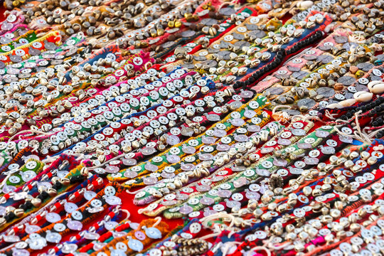 Assorted colorful handmade Indian bracelets and anklets decorated with metal charms, coins, bells and embroidery on display at a market in Hampi, India. Traditional ethnic fashion accessories.