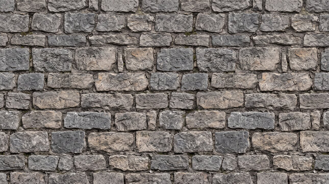 A detailed texture of an old grey stone wall with irregular blocks and mortar.