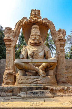 Colossal monolithic statue of Hindu god Narasimha under a multi-headed serpent canopy in Hampi, India. Historic ancient stone sculpture, cultural heritage landmark and archaeological attraction.