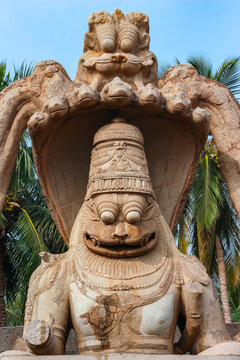 Colossal monolithic statue of Hindu god Narasimha under a multi-headed serpent canopy in Hampi, India. Historic ancient stone sculpture, cultural heritage landmark and archaeological attraction.