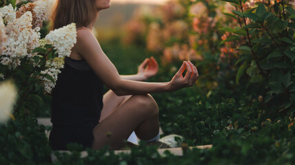 Naklejka premium Woman meditating peacefully in a lush garden at sunset