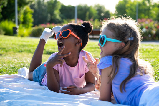 Diverse girls lying on a blanket in the park enjoying summer friendship and fun