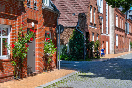 Husum, Germany. Historic brick houses with blooming roses line a quiet residential street in the old town of Husum, creating a typical northern German atmosphere.