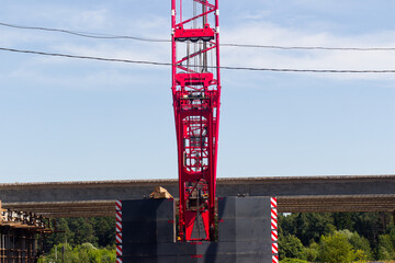 Tower crane metal boom standing tall against the sky at a highway overpass construction site, massive heavy machinery operating during road infrastructure improvement and bridge building © PhotoChur