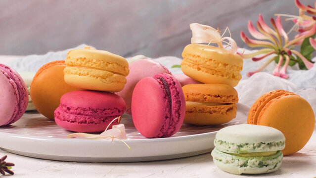 Assortment of colorful French macarons on a plate with honeysuckle flowers
