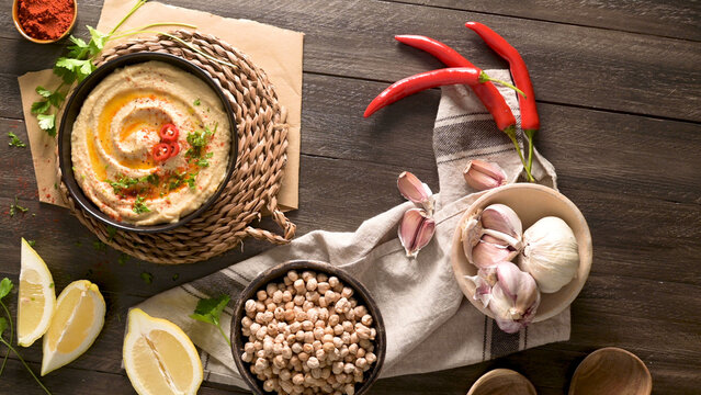 Homemade chickpea hummus served with garlic lemon and chili on rustic wooden surface