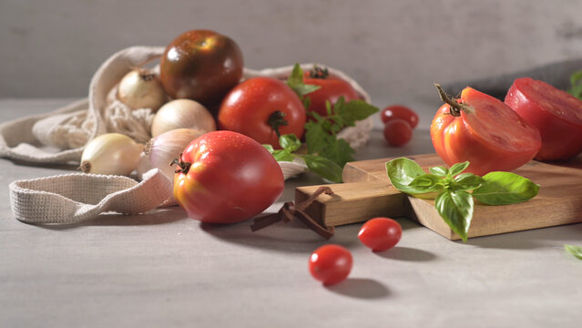 Fresh tomatoes and onions with basil on a wooden board