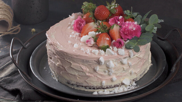 Gourmet cake with strawberries and pink roses on a dark tray