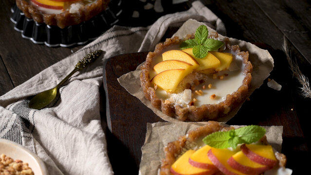 Mini peach tarts with coconut and mint on a wooden board