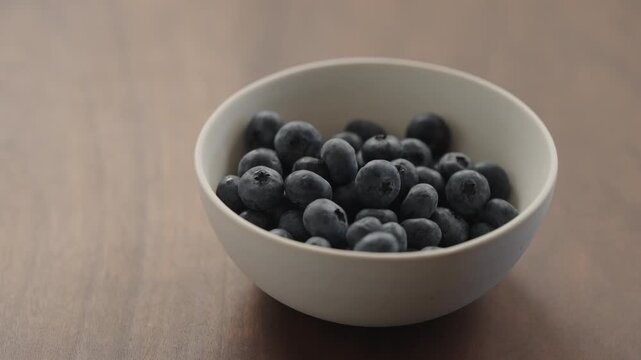 Slow motion man hand check blueberries in a ceramic bowl
