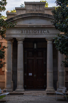Historic classic library building entrance facade with stone columns and wooden door.
