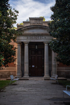 Historic classic library building entrance facade with stone columns and wooden door.
