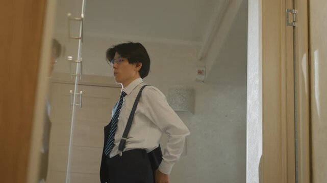Man getting ready calmly. Man in suit fixing his attire in peaceful hallway moments before wedding. Young man dressed in formal wear focusing on his accessories prior to wedding ceremony