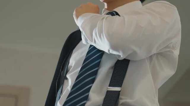 Man buttoning vest and adjusting tie before departure medium and closeup angles capture hands securing buttons, pulling suspenders into place, and straightening striped tie low camera angles emphasize