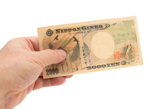 A hand holding a rare 2,000 Japanese yen banknote (reverse side showing Murasaki Shikibu and Tale of Genji). Scarce currency. Isolated on white background. Finance and collectibles.