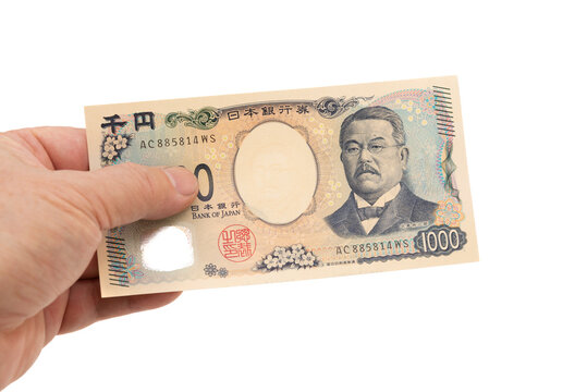 A hand holding a new 1,000 Japanese yen banknote (front side displaying Kitasato Shibasaburo portrait). Latest series (Series E) currency. Isolated on white background.