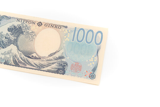 Top view of the reverse side of a new 1,000 Japanese yen banknote featuring Hokusai's The Great Wave off Kanagawa. Currency isolated on white background. Finance concepts.