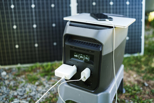 Portable power station with foldable solar panel charging electronic devices outdoors