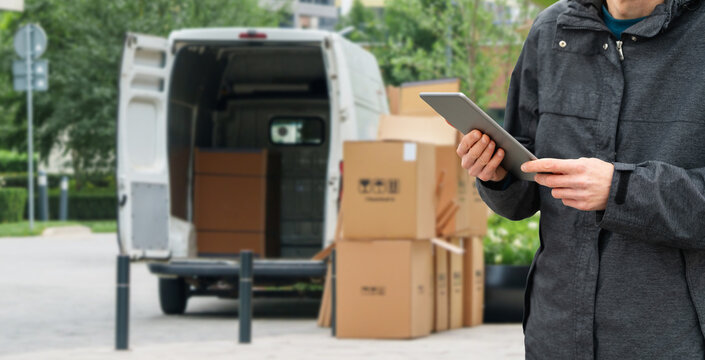 Courier holding a tablet computer with freight van and shipping packages in the background