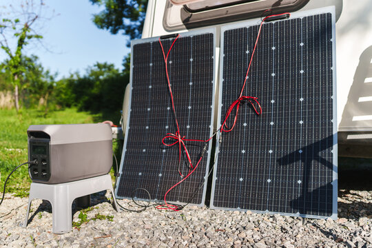 Portable power station with solar panels near a travel trailer caravan