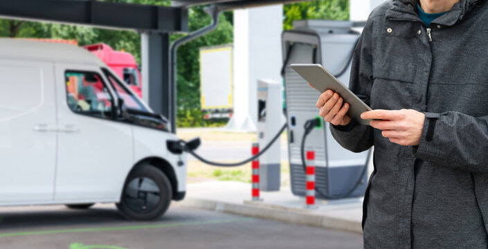 Fleet manager with digital tablet supervising electric delivery vans
