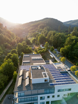 High-angle view of rooftop photovoltaic panels on a sleek urban building at golden hour