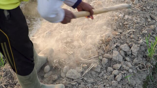 top down closeup of farmer raking dry dusty soil during golden hour. Extreme El Nino drought and climate change impact threatening agriculture in Southeast Asia.