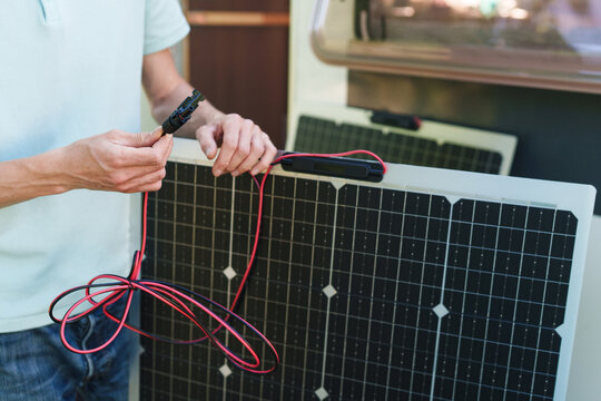 Close-up of technician hands connecting MC4 cables to a solar panel
