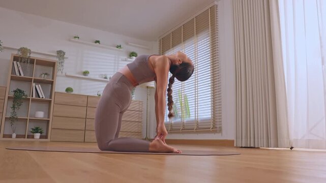 Woman yoga mat home exercise kneeling stretch backbend indoor wellness fitness pose calm focus bright room window floor posture
