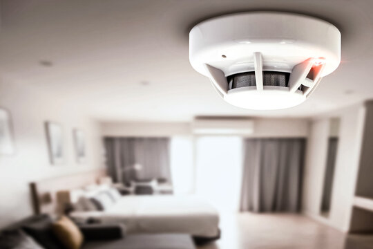 Smoke detector, fire alarm detector, and home safety device setup on the ceiling of a home hotel room.