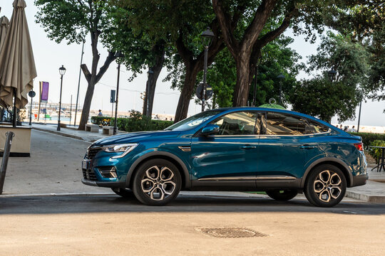Bari, Italy - June 31, 2026: Renault Arkana coupe SUV in teal blue parked on urban promenade near waterfront with trees and lampposts in background