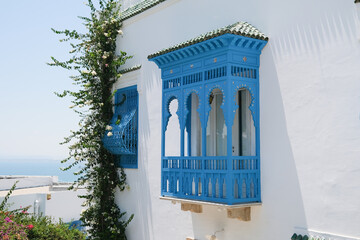 Fototapeta premium White Building with Blue Shutters and Bougainvillea in Mediterranean Town