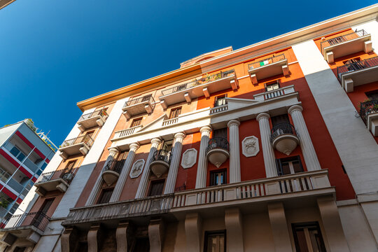 Historic building facade in Bari, Italy with classical columns and wrought iron balconies against deep blue sky, concept of Mediterranean architecture and urban heritage