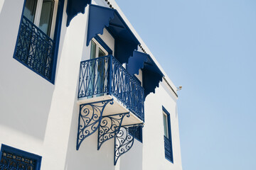 Fototapeta premium White Building with Blue Shutters and Bougainvillea in Mediterranean Town