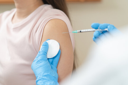 Close up of doctor in blue gloves giving vaccine injection to a female patient.